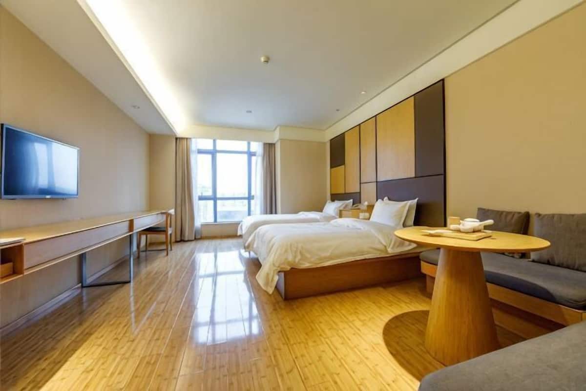 A hotel room with a bed, a desk, a TV, a sofa, and a round table.