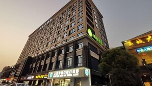 A multi-story hotel with a modern design, featuring a prominent sign for a hotel and a clinic on the ground floor. - JI Hotel (Shanghai Hongqiao National Exhibition and Convention Center) (Shanghai)