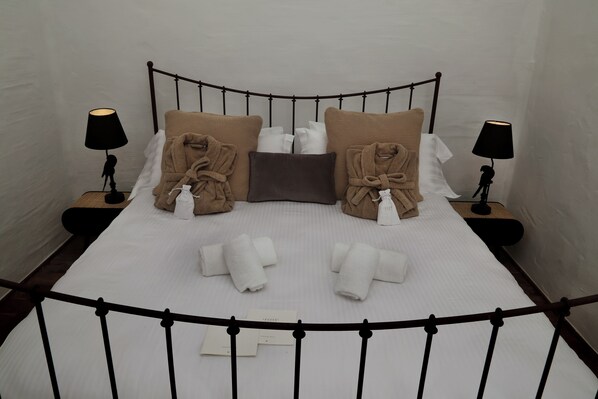 A neatly made bed with towels, pillows, and a bedside table with a lamp.