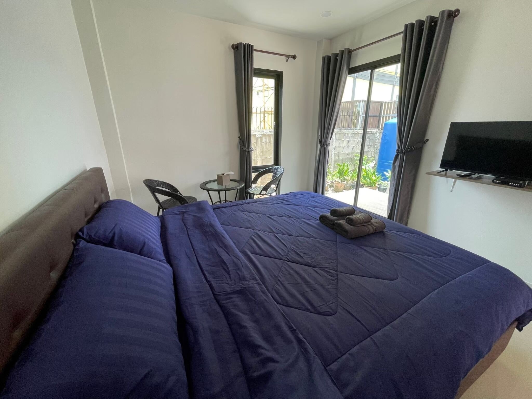 A hotel room with a bed, a television, a small table, and chairs.