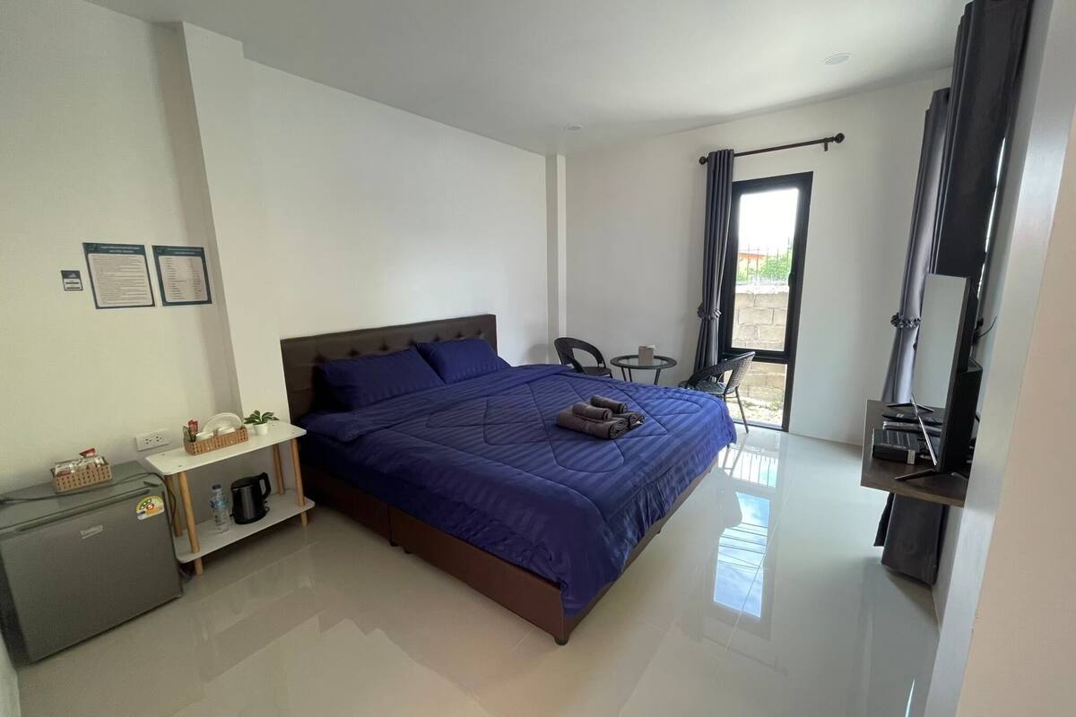 Un dormitorio moderno con una cama grande, un escritorio pequeño, una silla y un televisor.