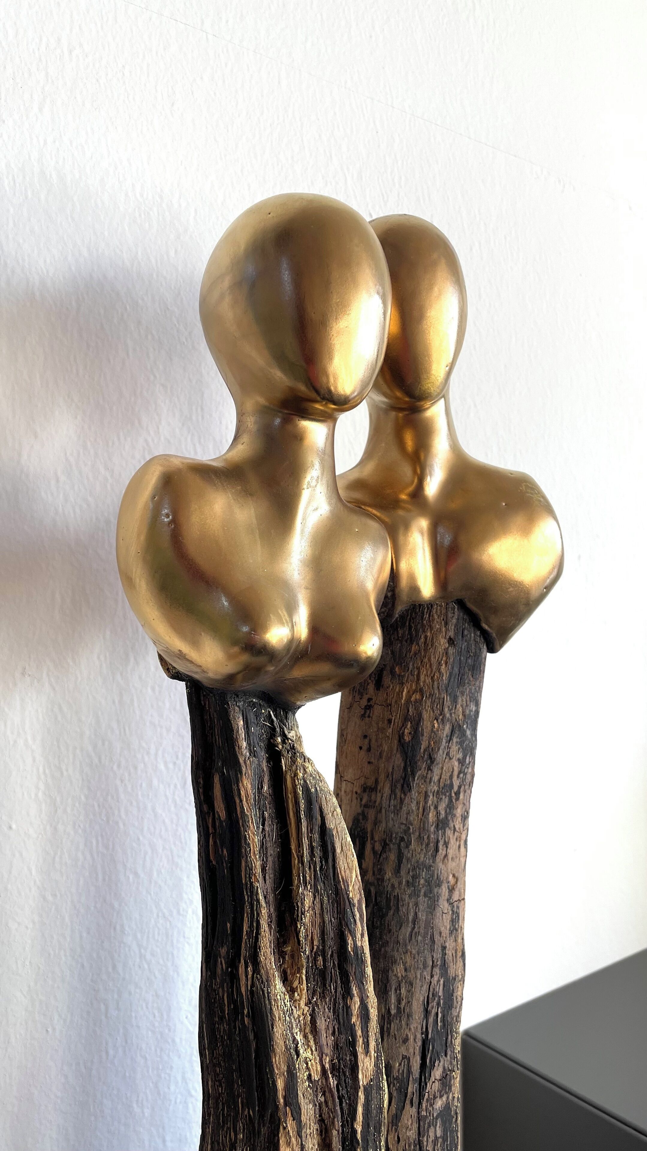 A decorative piece with two golden, bulbous shapes on a dark, textured base.