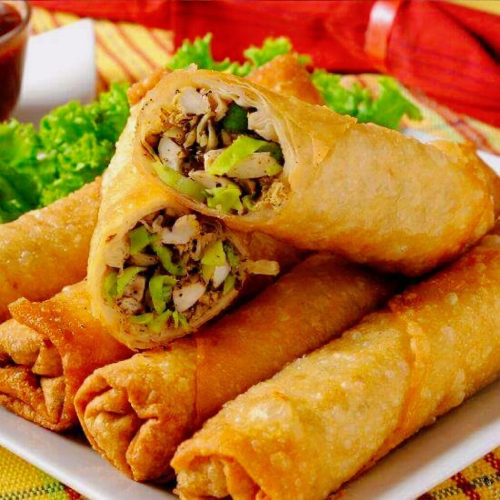 A plate of fried spring rolls with visible fillings of vegetables and possibly meat, served on a white plate with a green garnish.