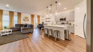 A modern kitchen with white cabinets, stainless steel appliances, and a central island with stools.