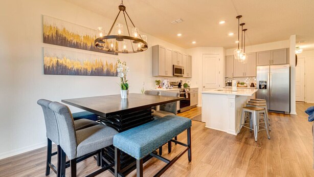 A modern kitchen with a central island, stainless steel appliances, and a chandelier.