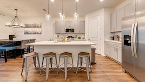 A modern kitchen with a central island, stainless steel appliances, and bar stools.