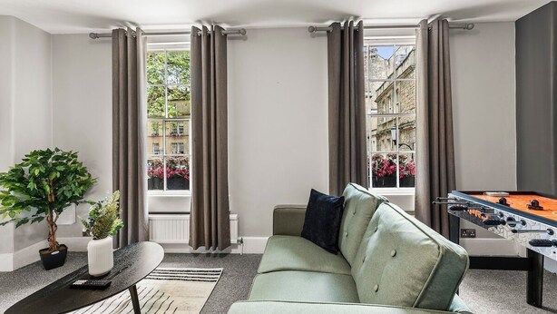 Un salon moderne avec un canapé, une table basse, une plante en pot et une table de baby-foot.