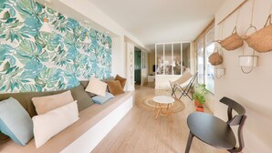 A modern living room with a sofa, a round table, and a chair. There is a wall with a leafy pattern and hanging lights. - Heated indoor swimming pool - oyster beds (Le Tour-du-Parc)