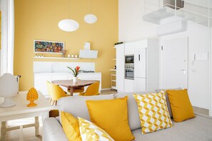 A modern living room with a sofa, yellow cushions, and a dining area with a table and chairs. - Helios Duplex a due passi da Ortigia by Wonderful Italy (Syracuse)