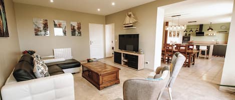Una sala de estar con un sofá, una mesa de centro y un televisor. Hay un comedor con una mesa y sillas.