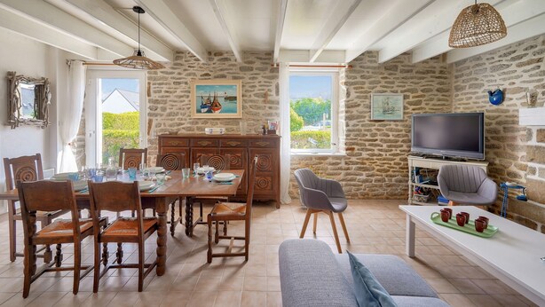 A dining area with a stone wall, wooden furniture, and a television in the background. - House for 7 300m from the beach - Guilvinec (Le Guilvinec)