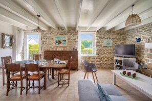 A dining area with a stone wall, wooden furniture, and a television in the background. - House for 7 300m from the beach - Guilvinec (Le Guilvinec)