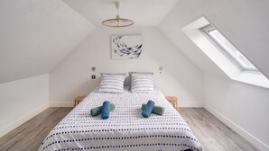 A bedroom with a sloped ceiling, a skylight, a bed with a polka dot bedspread, and a wall-mounted artwork. - House for 7 300m from the beach - Guilvinec (Le Guilvinec)