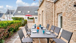An outdoor dining area with a stone building, a table set with chairs, and a red umbrella. - House for 7 300m from the beach - Guilvinec (Le Guilvinec)