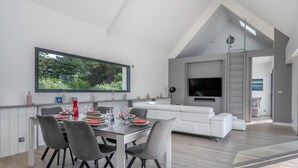 A modern living space with a dining area, a white sofa, and a TV.
