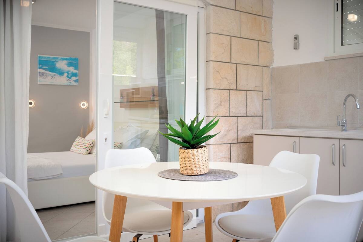 A modern kitchen with a white countertop, a sink, and a potted plant on the table.