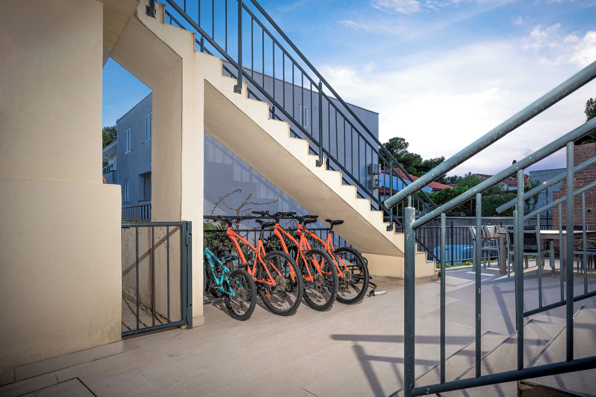 Una escalera con barandilla de metal y varios objetos similares a bicicletas estacionadas abajo.