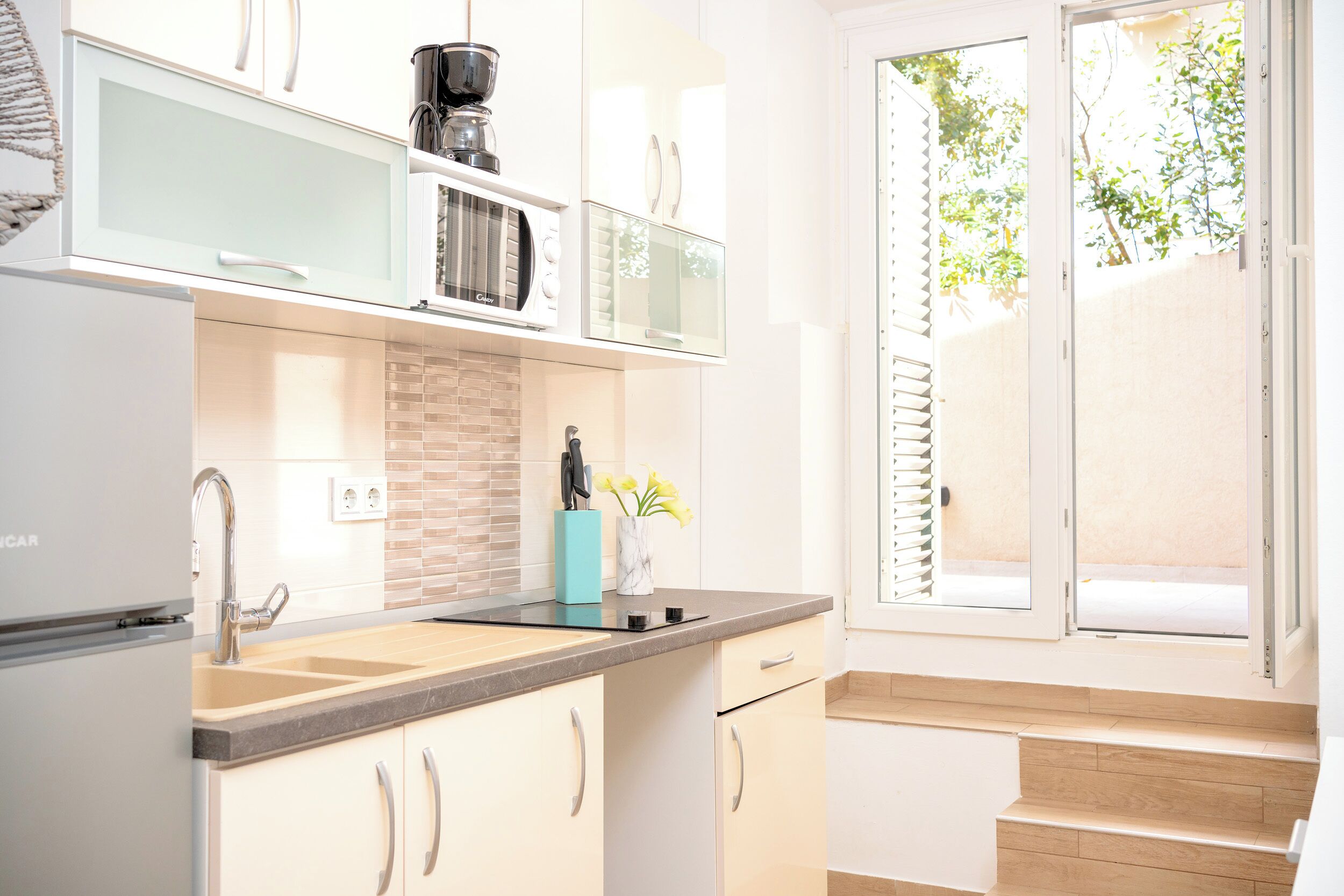 A modern kitchen with a built-in microwave, a sink, and a window with blinds.