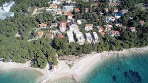 An aerial view of a coastal residential area with houses, a beach, and clear turquoise waters. - Beachfront Villa near Zlatni rat (Bol)