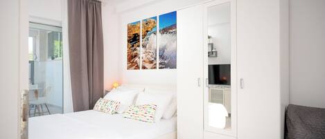 Une chambre à coucher moderne avec un lit, une armoire et un téléviseur.