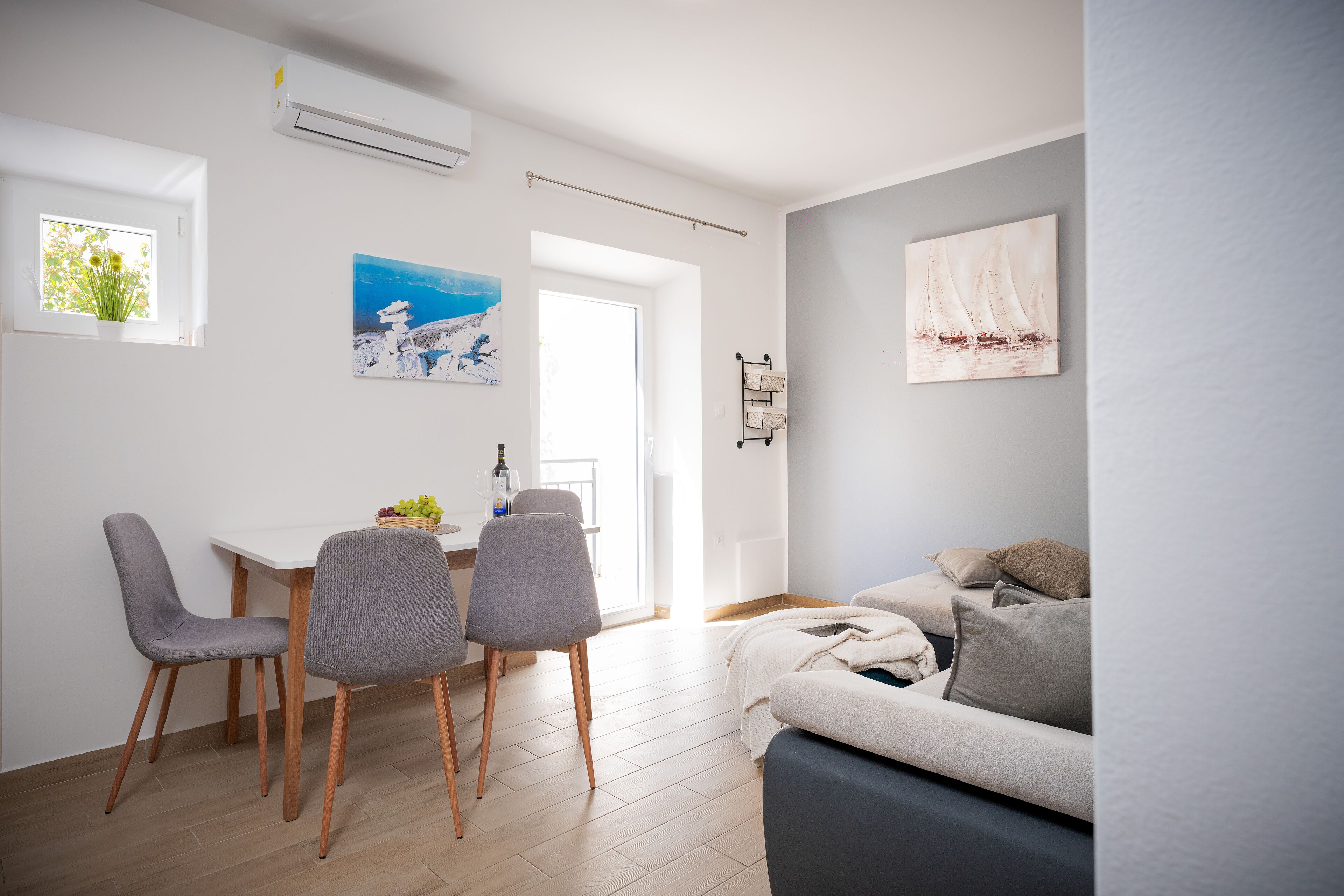Ein modernes Wohnzimmer mit einer Couch, einem Esstisch mit Stühlen und Kunstwerken an den Wänden.