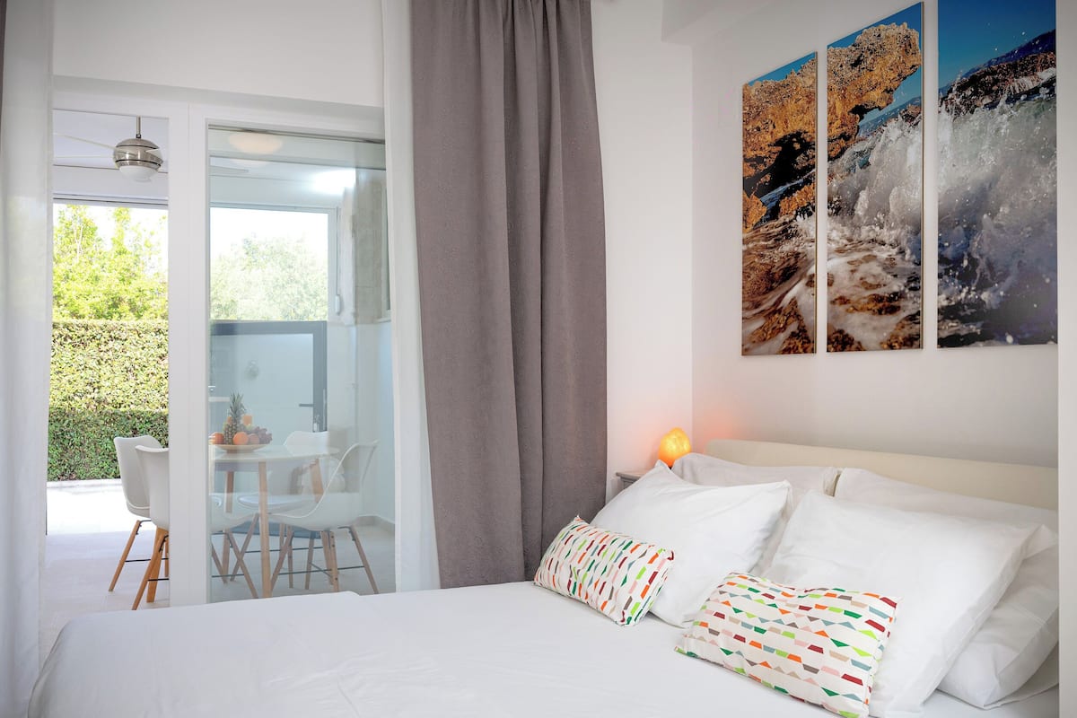 A hotel room with a large bed, a desk with chairs, and a view of the outdoors.