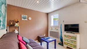 A room with a bed, a small table, a TV, and a window.