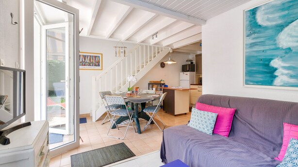 A cozy living area with a sofa, a dining table, and a kitchen in the background.