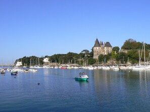 Overlooking a tranquil harbor, this property offers stunning views of a historic castle surrounded by lush greenery and a variety of boats.