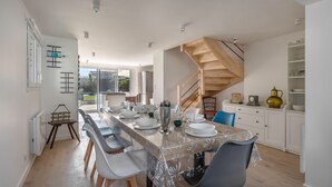A modern kitchen with a wooden staircase, a dining area with a table set for four, and a view of the outdoors. - Family house 400m from the sea for 8, Pornic (Pornic)