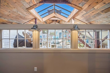 A room with a skylight, wooden ceiling beams, and a wall with framed pictures.. En suites | Walkable to cider house & coffee shop