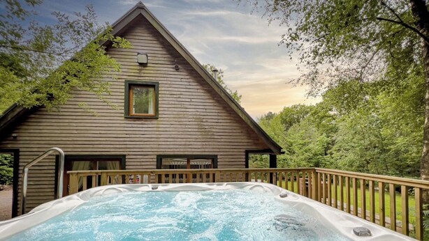 Eine Holzhütte mit Whirlpool davor.