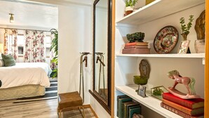 A bedroom with a bed, a wooden chair, a mirror, and a bookshelf with books and decorative items. - Quaint walkable to Downtown Cashmere (Cashmere)