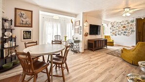 A dining area with a round table and chairs, a television, and a wall decorated with plates. - Quaint walkable to Downtown Cashmere (Cashmere)