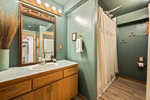 A bathroom with a wooden vanity, a large mirror, and a shower curtain.
