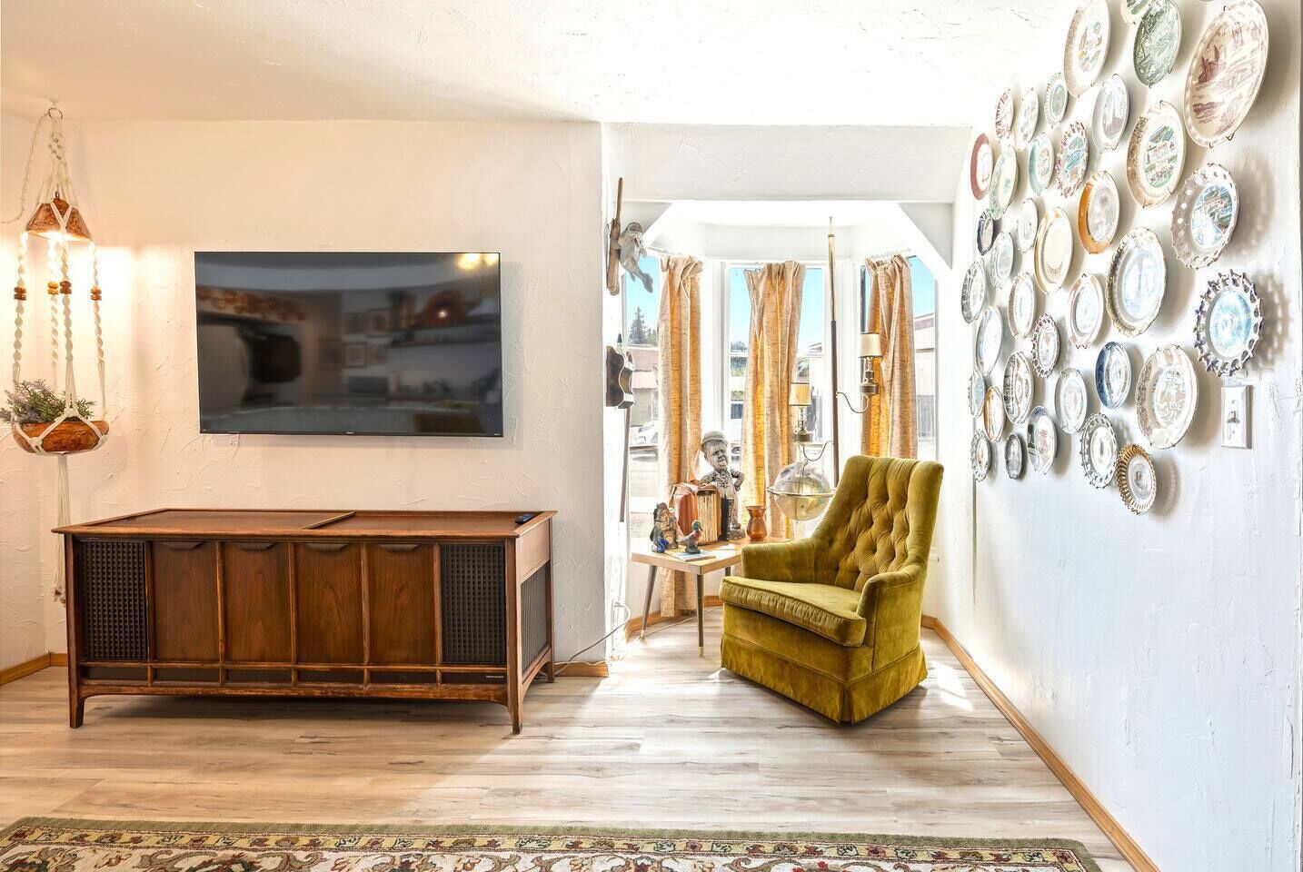A living room with a wooden entertainment center, a television, a green armchair, and a wall decorated with bottle caps.