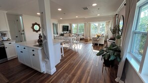 A spacious kitchen with white cabinetry, a central island, and a dining area with white chairs. - Treetop getaway on a secluded Island with gulf coast beaches  (Captiva)