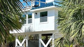 A two-story building with a blue roof, surrounded by palm trees. - Treetop getaway on a secluded Island with gulf coast beaches  (Captiva)