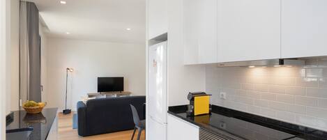 A modern kitchen with white cabinets, a black countertop, and stainless steel appliances.