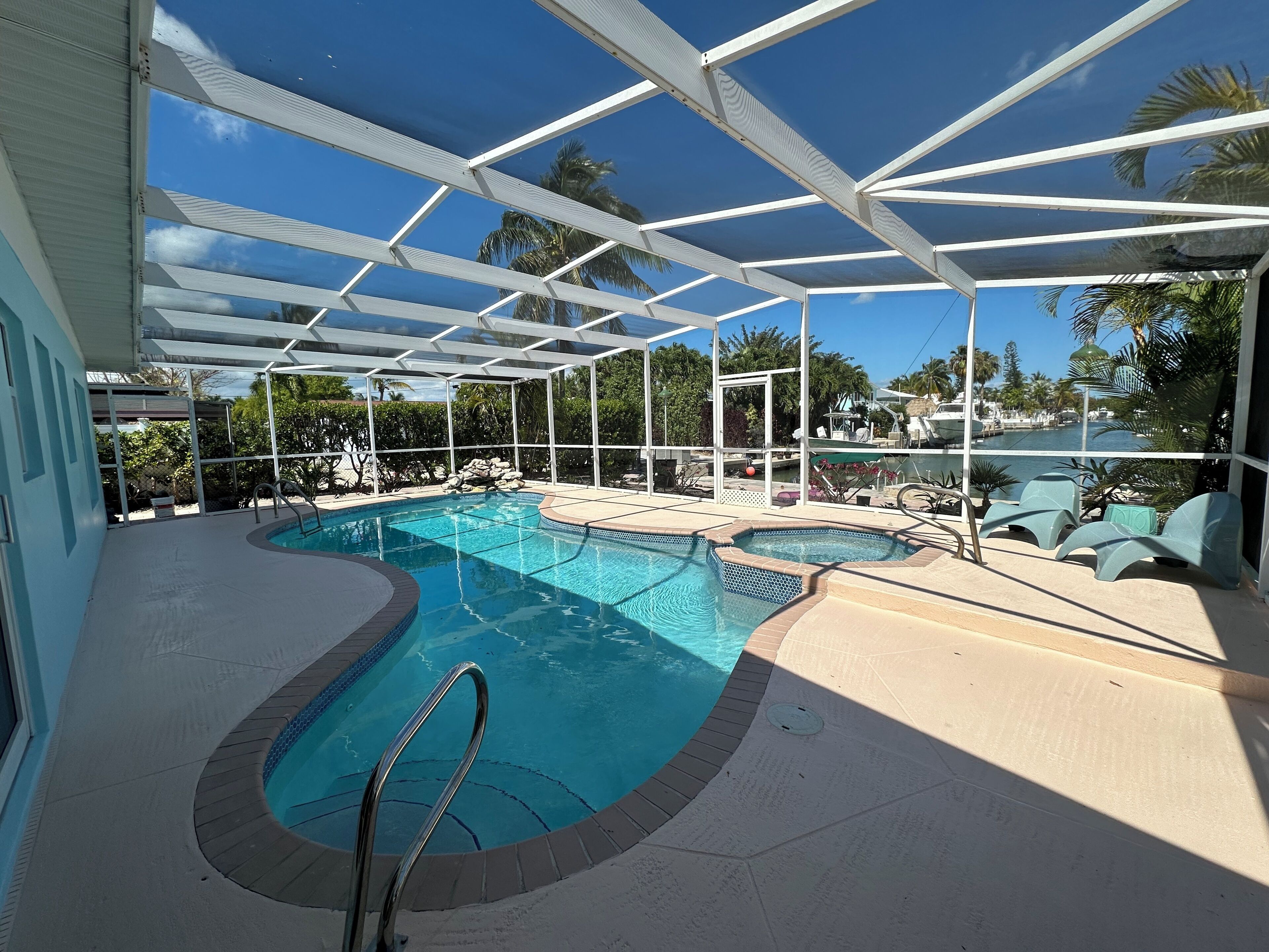 An indoor swimming pool with a glass ceiling, multiple pool sections, and lounge chairs.