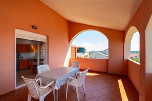 A balcony with a table and chairs, a view of the city, and a kitchen area. - Comfortable Apartments Malina A4 br 3 (Novalja)