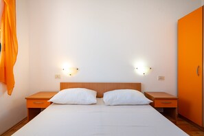 Une chambre d’hôtel avec un lit, deux tables de chevet et une armoire.