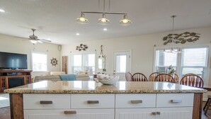 A spacious kitchen with a large island, white cabinetry, and a dining area with wooden chairs. - Large Home Near the Caney Y with Pool! (Bay City)