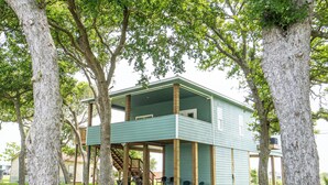 Un bâtiment à deux étages doté d’un balcon, entouré d’arbres.