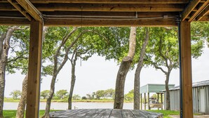 Une table de pique-nique en bois rustique, placée sous un espace abrité, avec des arbres en arrière-plan.