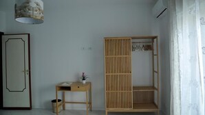 Una habitación minimalista con un armario de madera, un pequeño escritorio con una planta y una lámpara colgante.