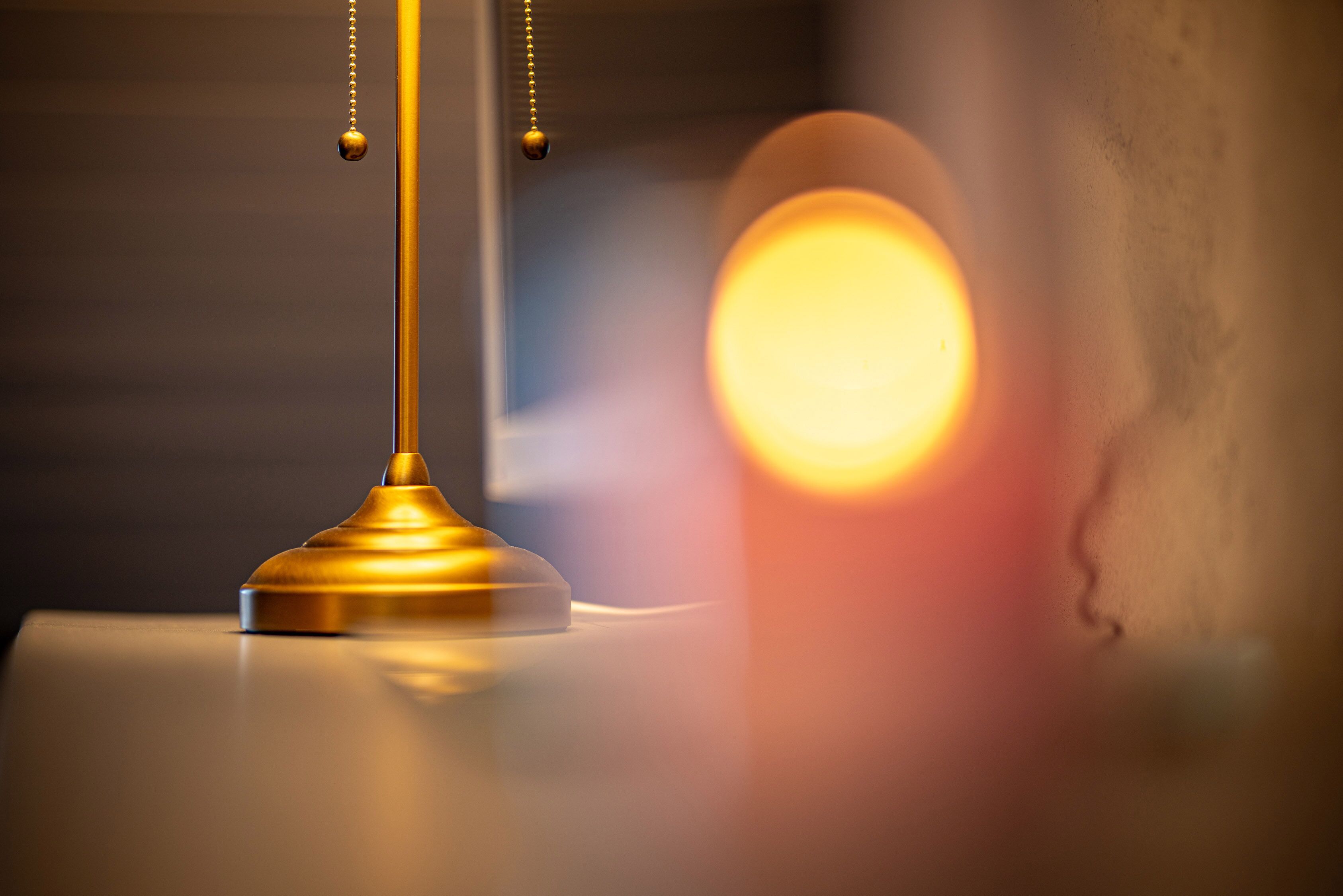 A close-up of a lamp with a golden base and a hanging spherical ornament.