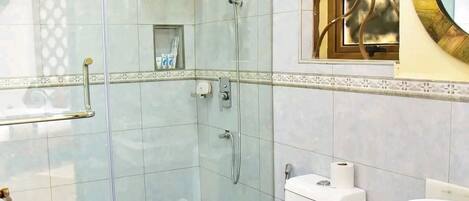 A modern bathroom with a glass-enclosed shower, a white toilet, and a vanity with a large mirror.