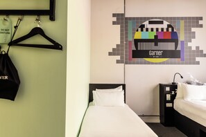 A hotel room with a bed, a nightstand, a lamp, and a wall with a pixelated Garner logo. - Garner Hotel Dublin Temple Bar by IHG (Dublin)