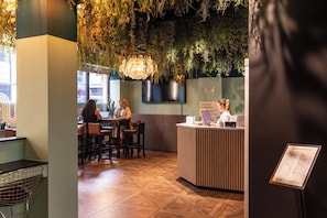 A reception area with a counter, seating, and a wall decorated with plants. - Garner Hotel Dublin Temple Bar by IHG (Dublin)